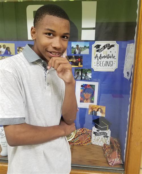 Eighth grade student stands in front of display  